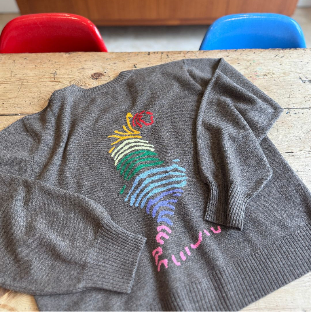 brown grey cardigan with a rainbow tiger design on the back on a table