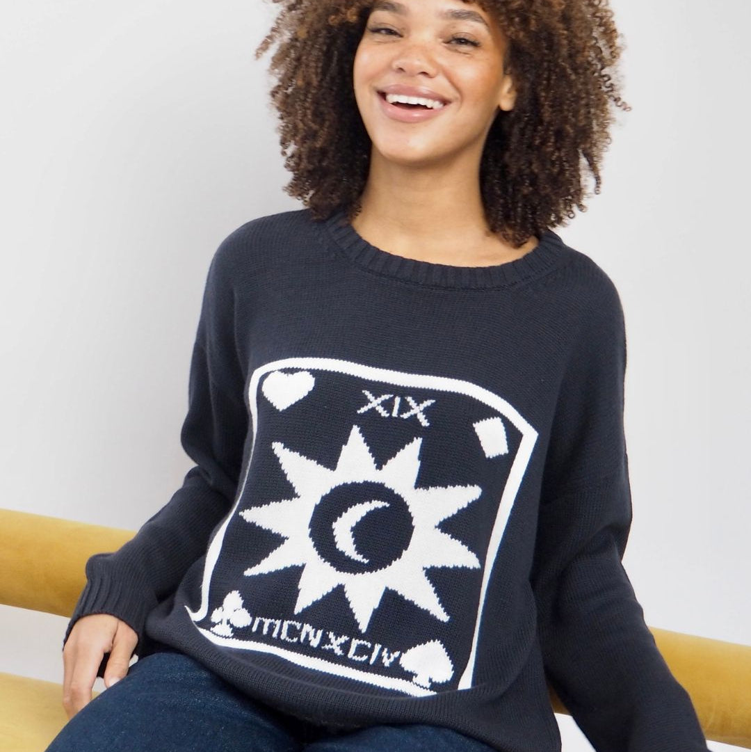 Person wearing a navy blue sweater with a white graphic design on a white background